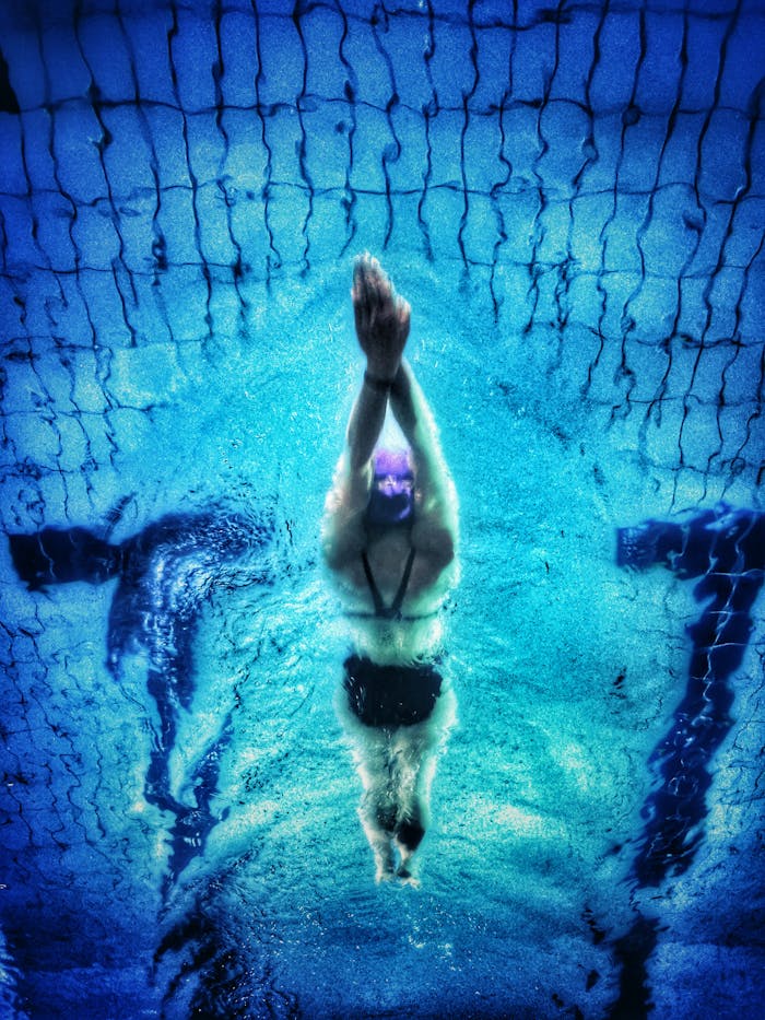 Captivating underwater shot of a swimmer in a pool with clear blue water.